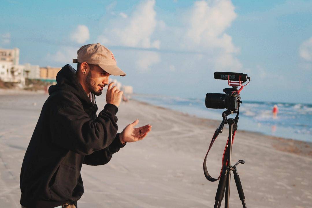 A man setting up a camera by the beach