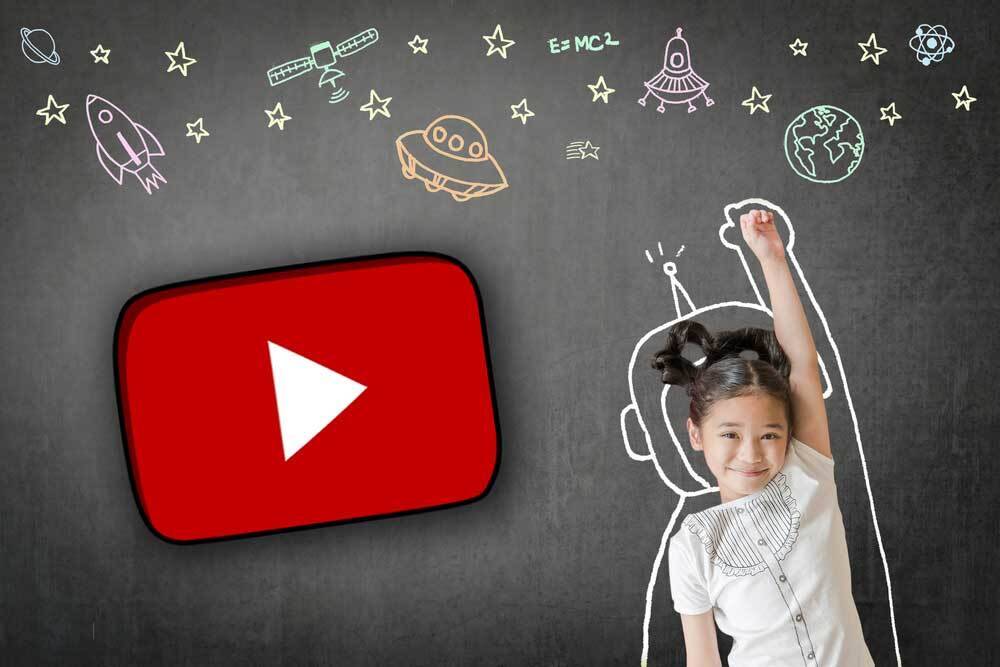 Smiling girl with raised arm and space doodles near YouTube play button on blackboard background