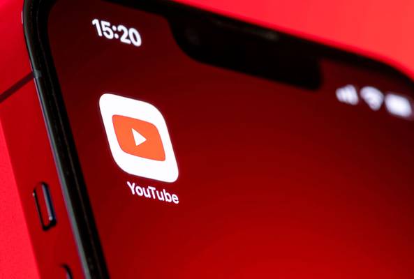 Close-up of smartphone screen showing YouTube app icon on a red background.