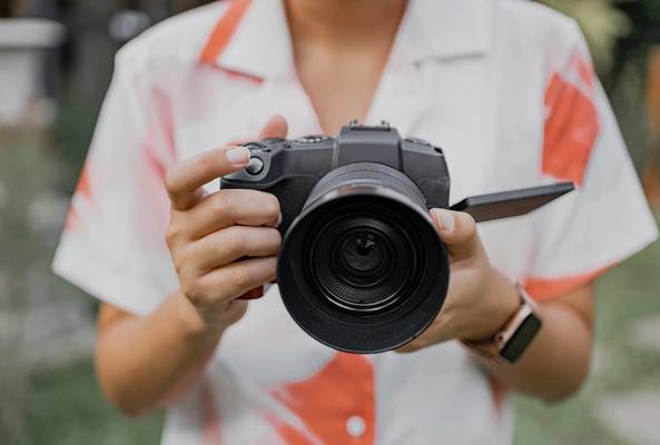 Person holding a DSLR camera with flip-out screen, ready to take a photo outdoors