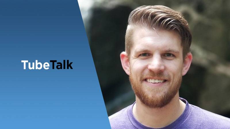 Smiling man with beard beside blue background and TubeTalk logo for video podcast.