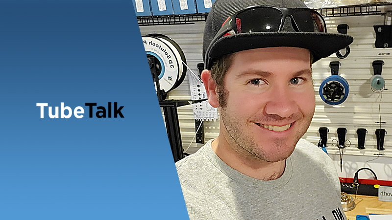 Smiling man in cap and sunglasses with fishing gear and TubeTalk logo on blue background