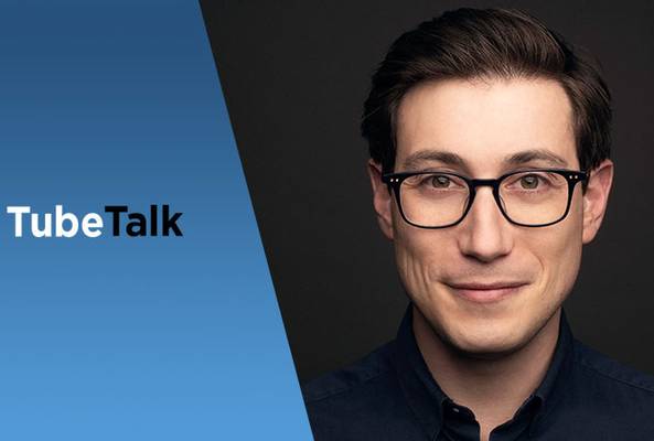 Young man with glasses on dark background next to blue TubeTalk logo graphic