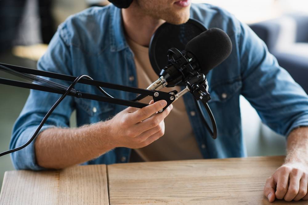 Person adjusting professional microphone arm for podcast or audio recording session.