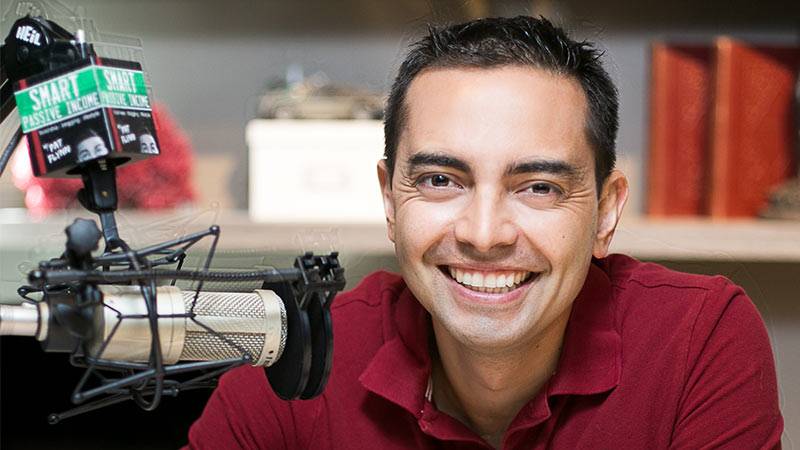 Smiling man recording a podcast with professional microphone in a casual indoor studio setting