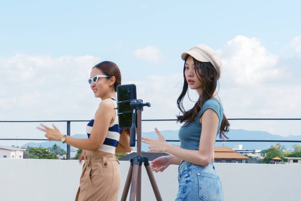 Two women filming a YouTube video on one phone