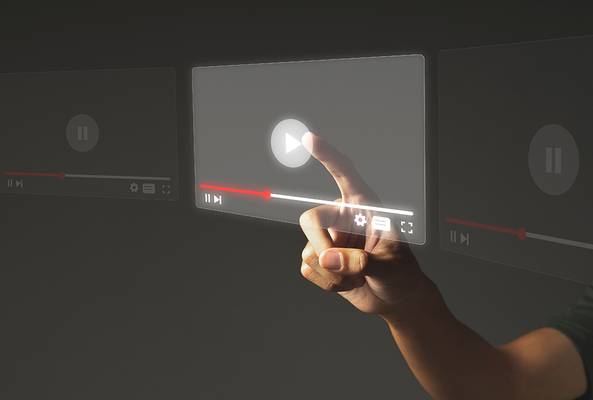 Hand pressing play button on futuristic transparent video player interface on screen