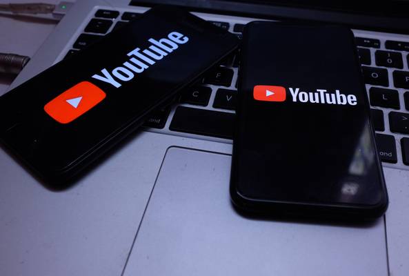Two smartphones displaying YouTube logo on a laptop keyboard, digital video concept.