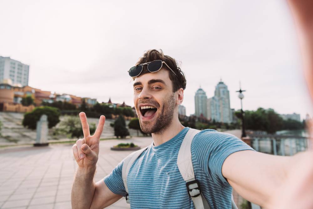 Man doing the peace sign with fingers while vlogging