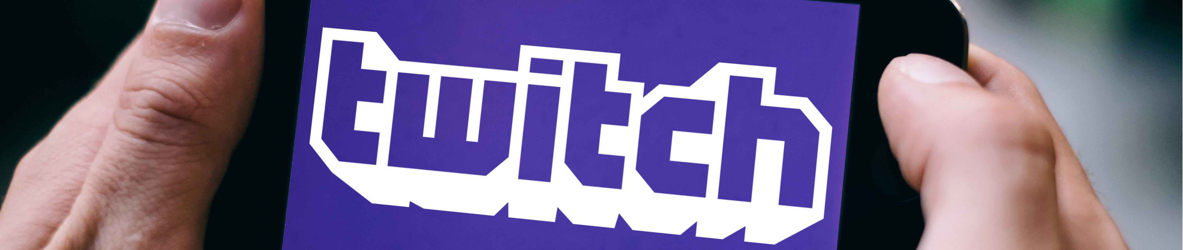 Close up of hands holding smartphone with the Twitch streaming platform logo on screen