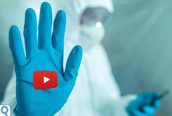 Person in protective suit showing a gloved hand with a red play button icon overlay