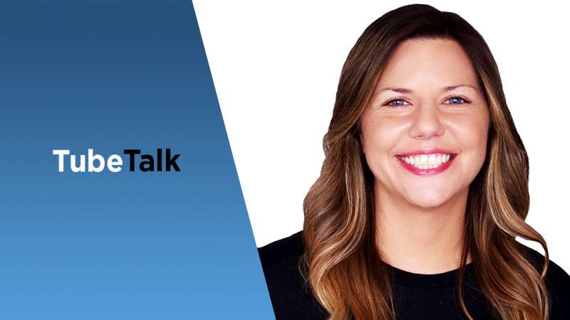Smiling woman with long hair on white background next to TubeTalk logo on blue panel.