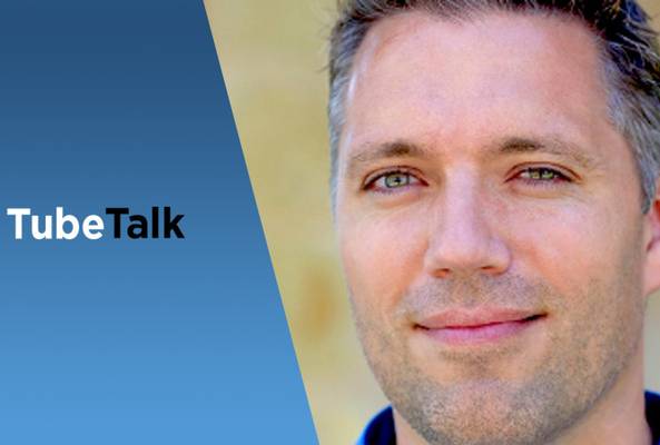 Close-up of man with blue background and TubeTalk logo for video podcast branding.