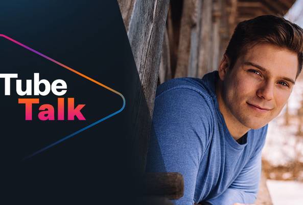 Tube Talk logo with a smiling young man leaning on a wooden structure outdoors in winter