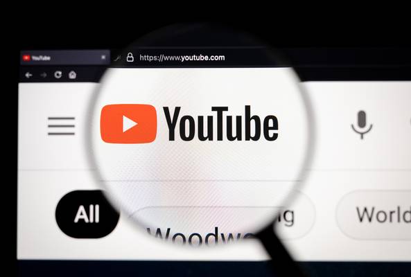 Magnified YouTube logo on website homepage viewed through a magnifying glass on screen