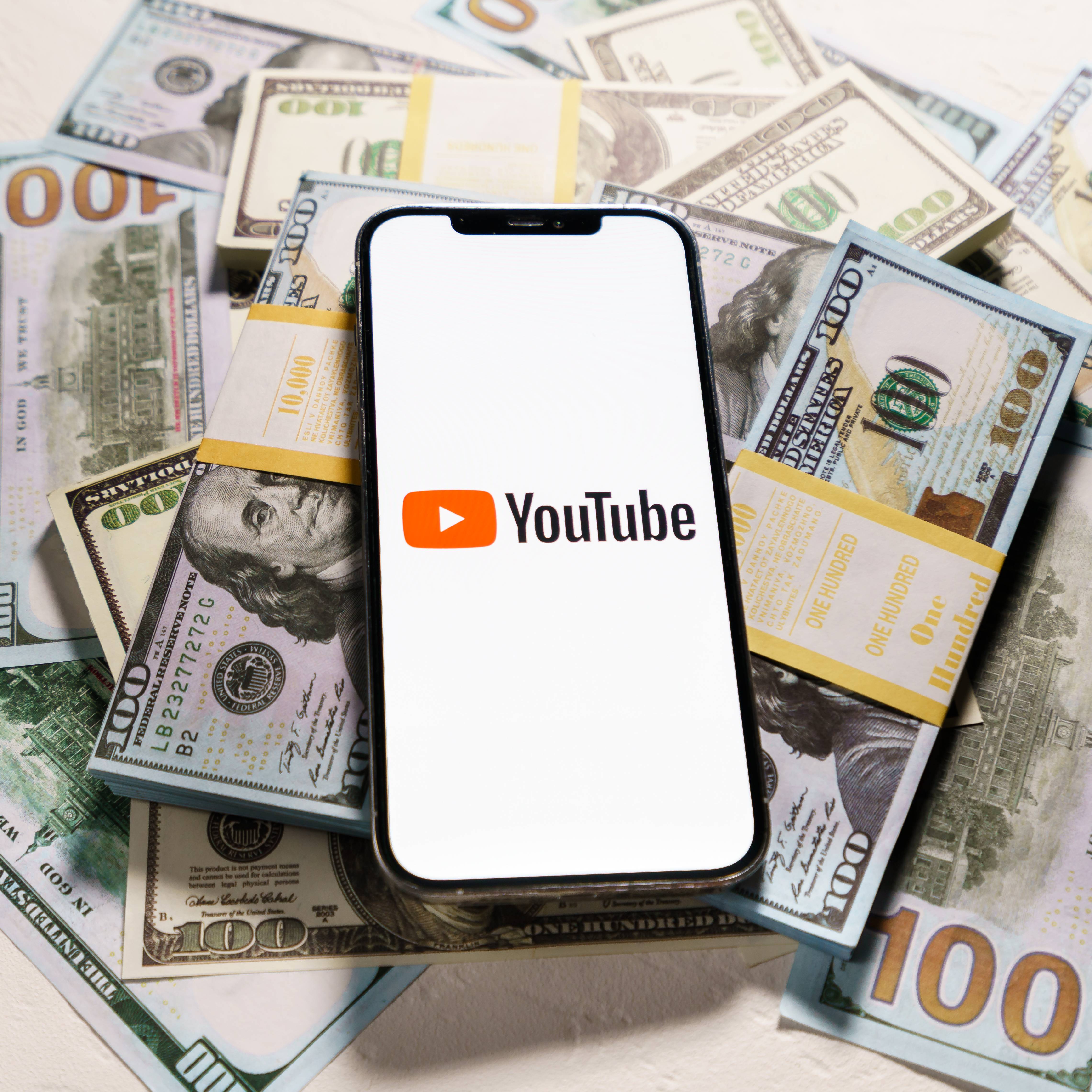 YouTube logo on phone with currency in background