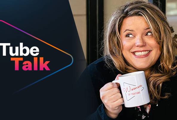 Woman smiling and holding a "Women of YouTube" mug with Tube Talk logo beside her