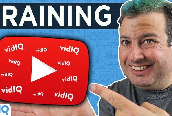 Smiling man pointing at a vidIQ YouTube play button icon with TRAINING text above.