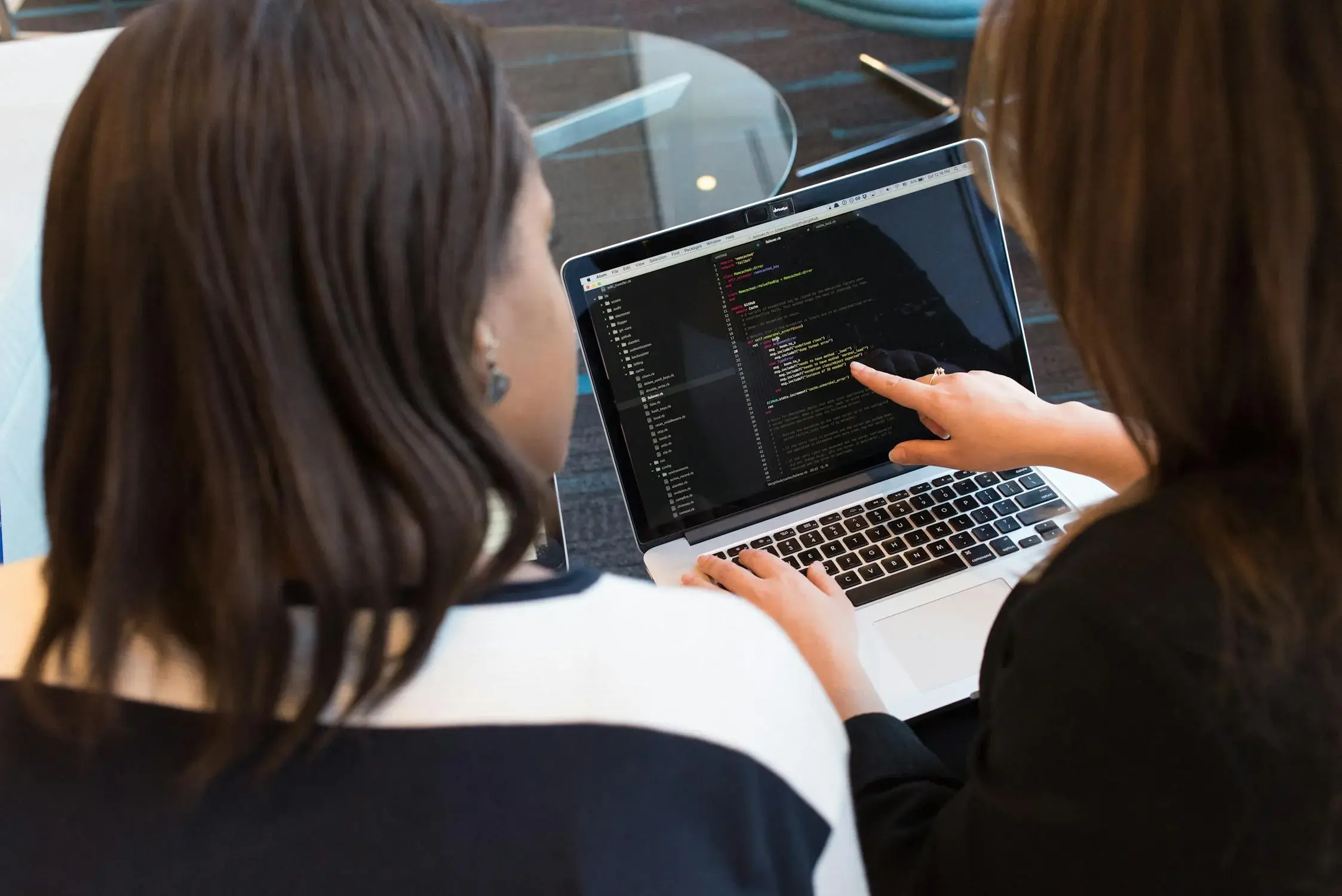 two woman pointing at the monitor
