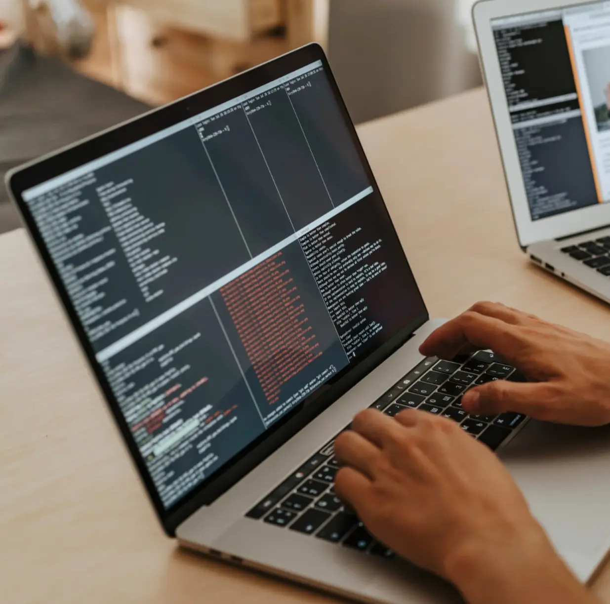 picture of a guy coding on a mac laptop in an office