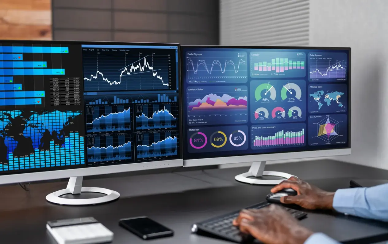 picture of a guy reviewing two screens with custom dashboards and reports