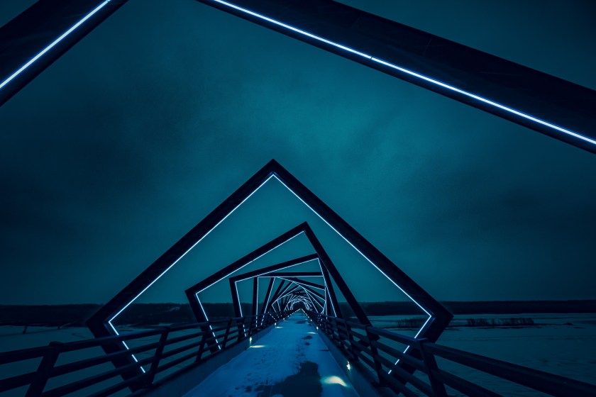 Geometric tunnel of nested diamond shapes with blue neon lighting creating a perspective view into depth.