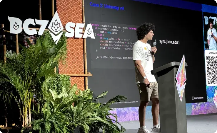 Speaker presenting at OGZASEA tech conference with code displayed on screen behind him and logo with tropical plants in foreground.