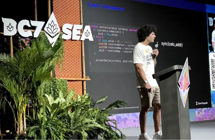 Speaker presenting at OGZASEA tech conference with code displayed on screen behind him and logo with tropical plants in foreground.