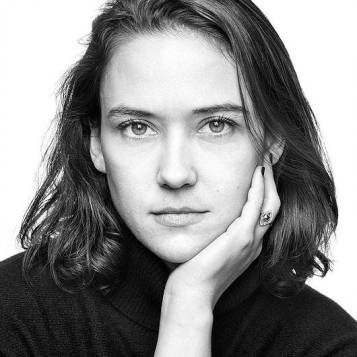 Professional headshot of a woman with shoulder-length dark hair in black and white.