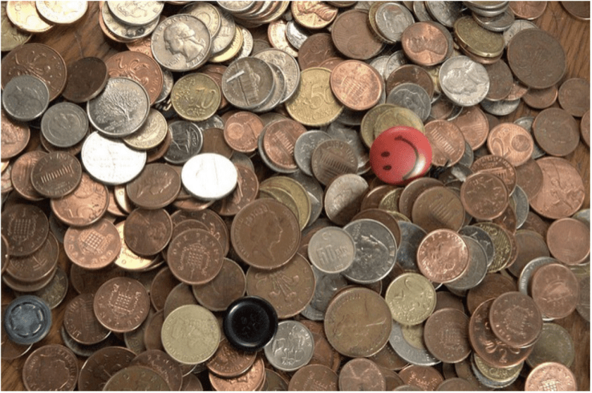 A red button and a black button placed among scattered coins of various denominations.