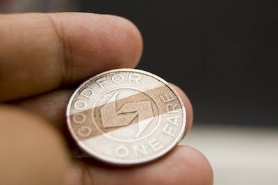 Hand holding a shiny penny coin showing the profile side against a dark background.