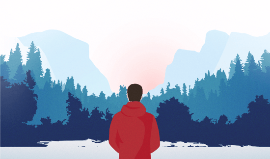 Person in red jacket standing before a forested mountain valley at sunrise or sunset.