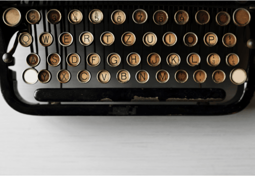 Vintage typewriter keyboard with brass letter keys arranged in QWERTY layout on black body.