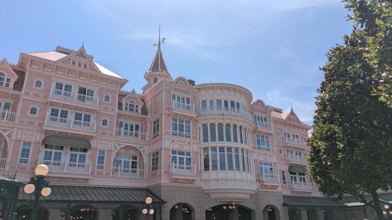 The image captures a large, intricately designed hotel building with a pink façade and Victorian architectural elements. The sky is clear, and the building is adorned with balconies and decorative features typical of a resort setting.