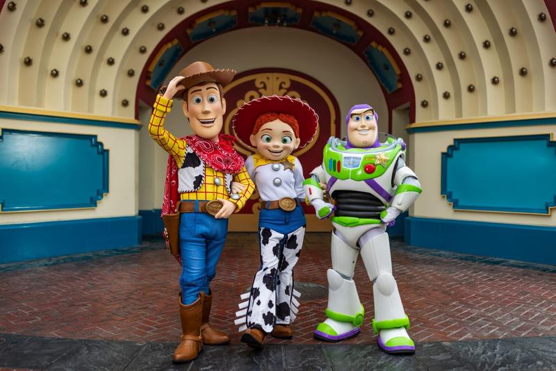 The image features three animated characters from the Toy Story franchise, standing together in a colorful setting. Woody, Jessie, and Buzz Lightyear are depicted in their iconic outfits, showcasing their distinct personalities.