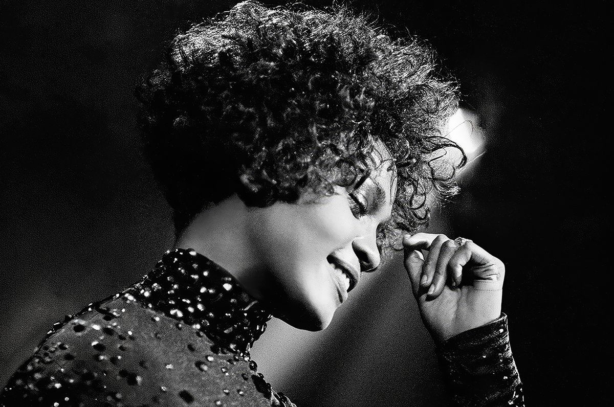 A black and white portrait of a singer with curly hair, captured in a moment of emotion and grace. The image highlights the artist's expression as they perform, evoking a sense of nostalgia and artistry.
