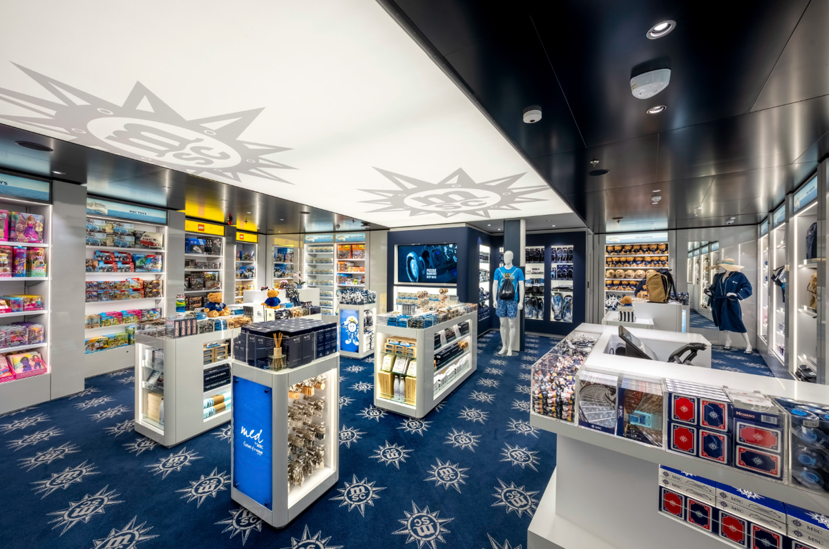 The image depicts a modern retail store interior featuring various merchandise displays. The bright lighting highlights a variety of toys and collectibles arranged on shelves, with a central checkout area visible.