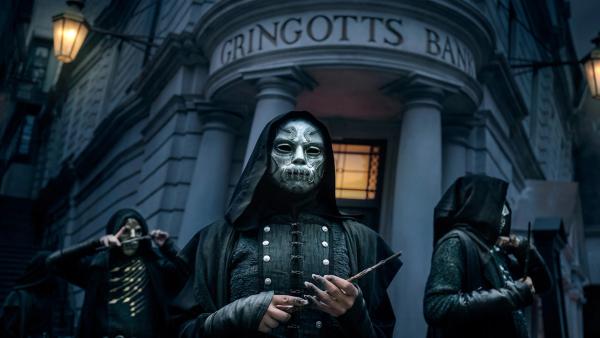 The image depicts a dark, atmospheric scene outside Gringotts Bank, featuring hooded figures wearing skull masks. They are holding various objects, possibly for a heist or ritual, creating a sense of intrigue and suspense.