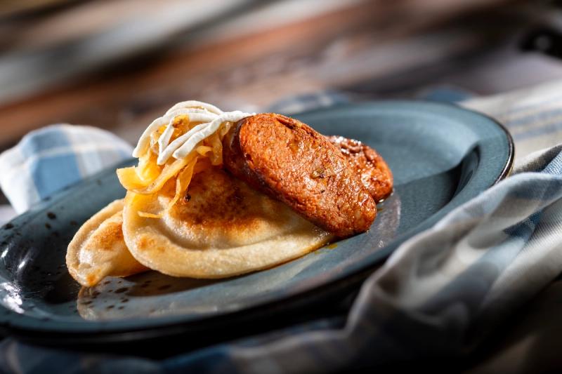 The image showcases a plate featuring a serving of pierogi, a traditional Eastern European dumpling. The dish is presented with a golden-brown filling alongside caramelized onion and garnished with sour cream.