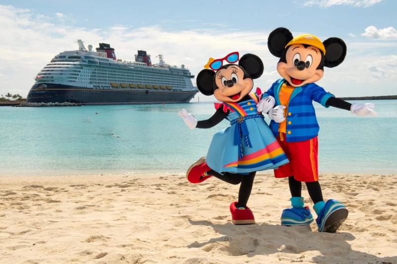 Mickey Mouse and Minnie Mouse pose on a beach with a Disney cruise ship in the background. The scene is bright and colorful, suggesting a festive atmosphere.