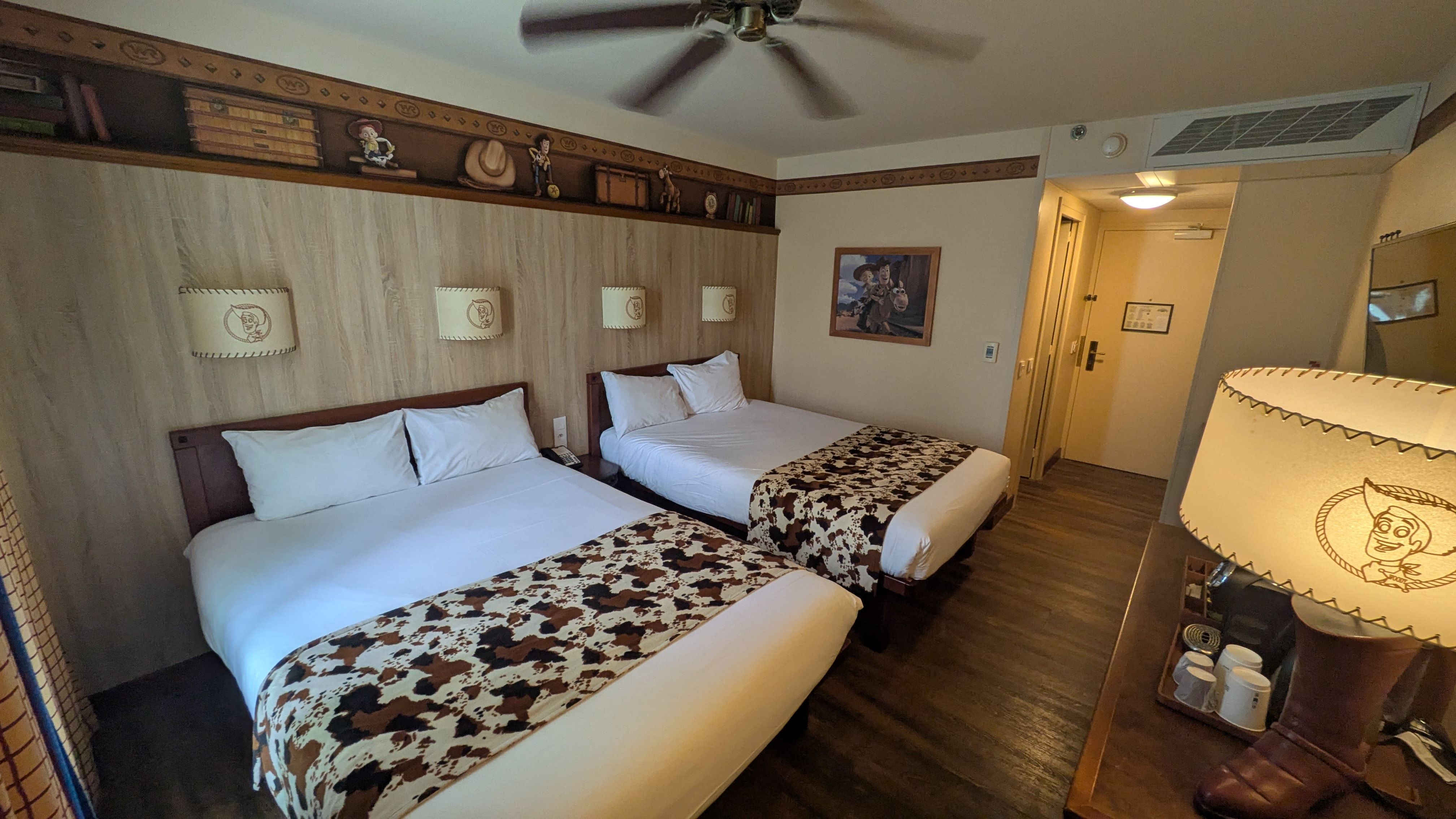 The image shows a well-decorated hotel room featuring two beds with themed bedding. The walls are adorned with decorative elements that suggest a playful, western or cowboy theme, typical for a family-friendly hotel.