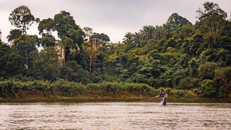 Fishing on the Tembeling river, with a swiflet bird nest farm in the background