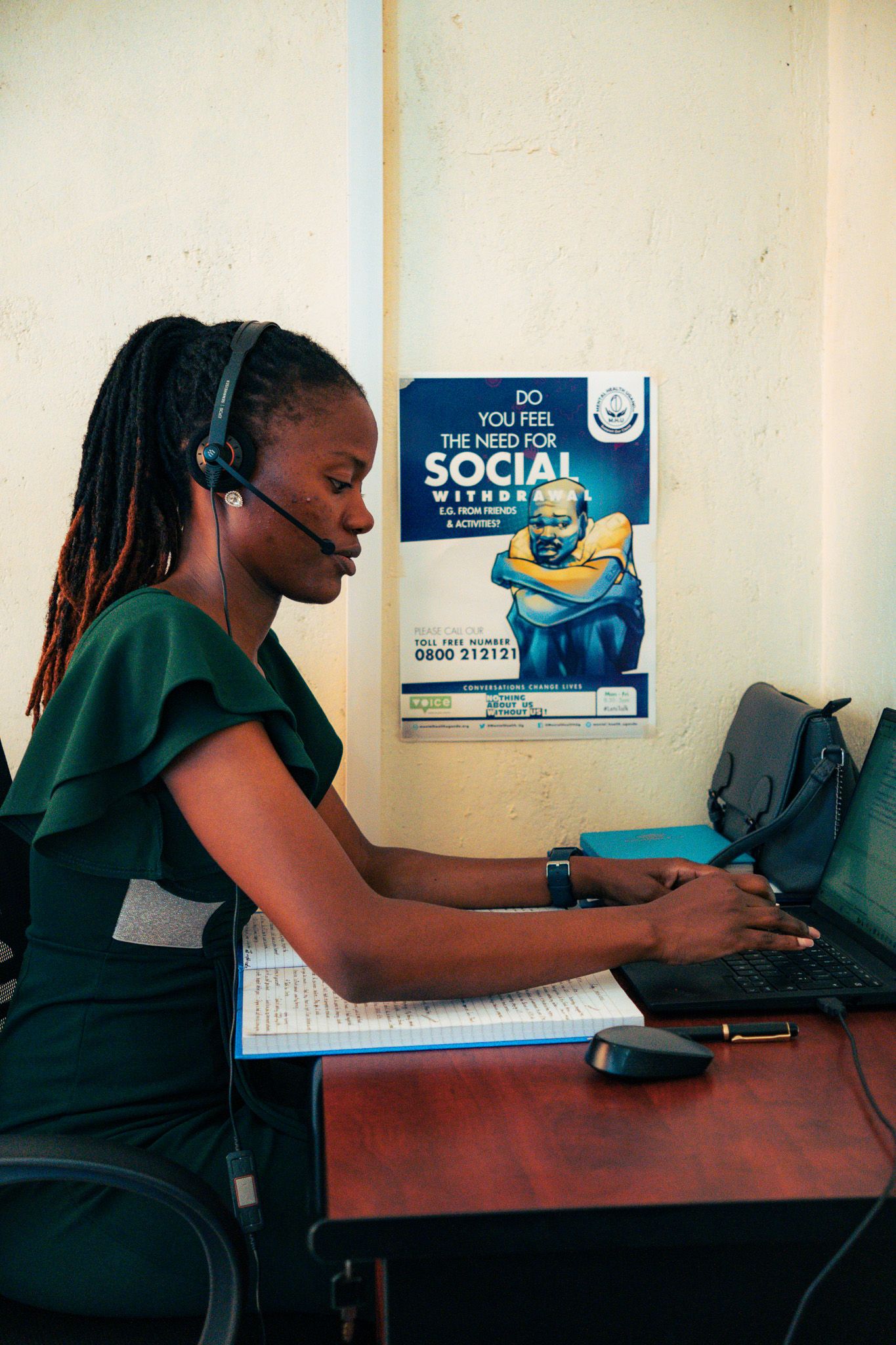 Dame med headset og PC ved en av våre hjelpetelefoner