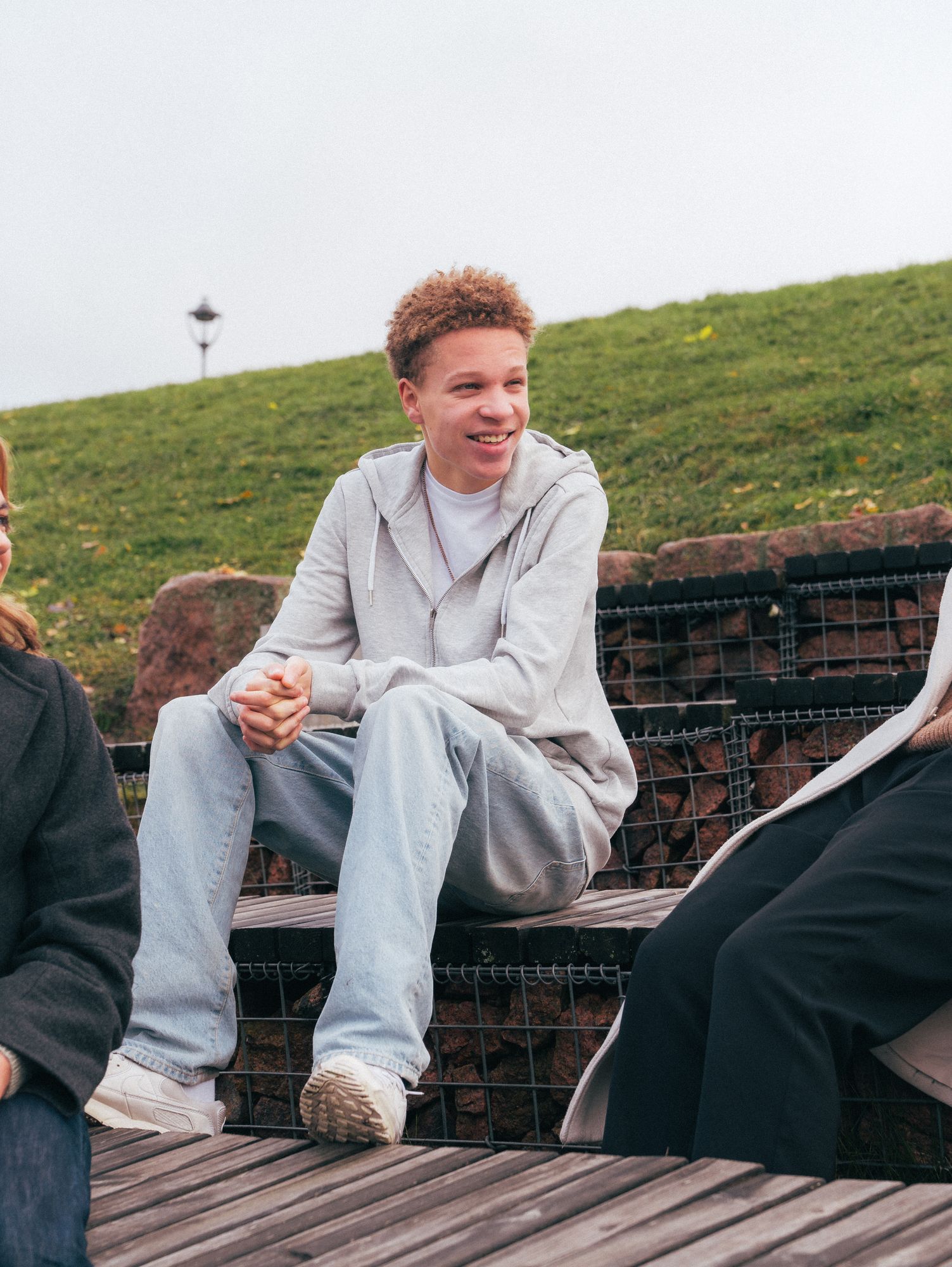 Tre ungdommer snakker og ler sammen i en park