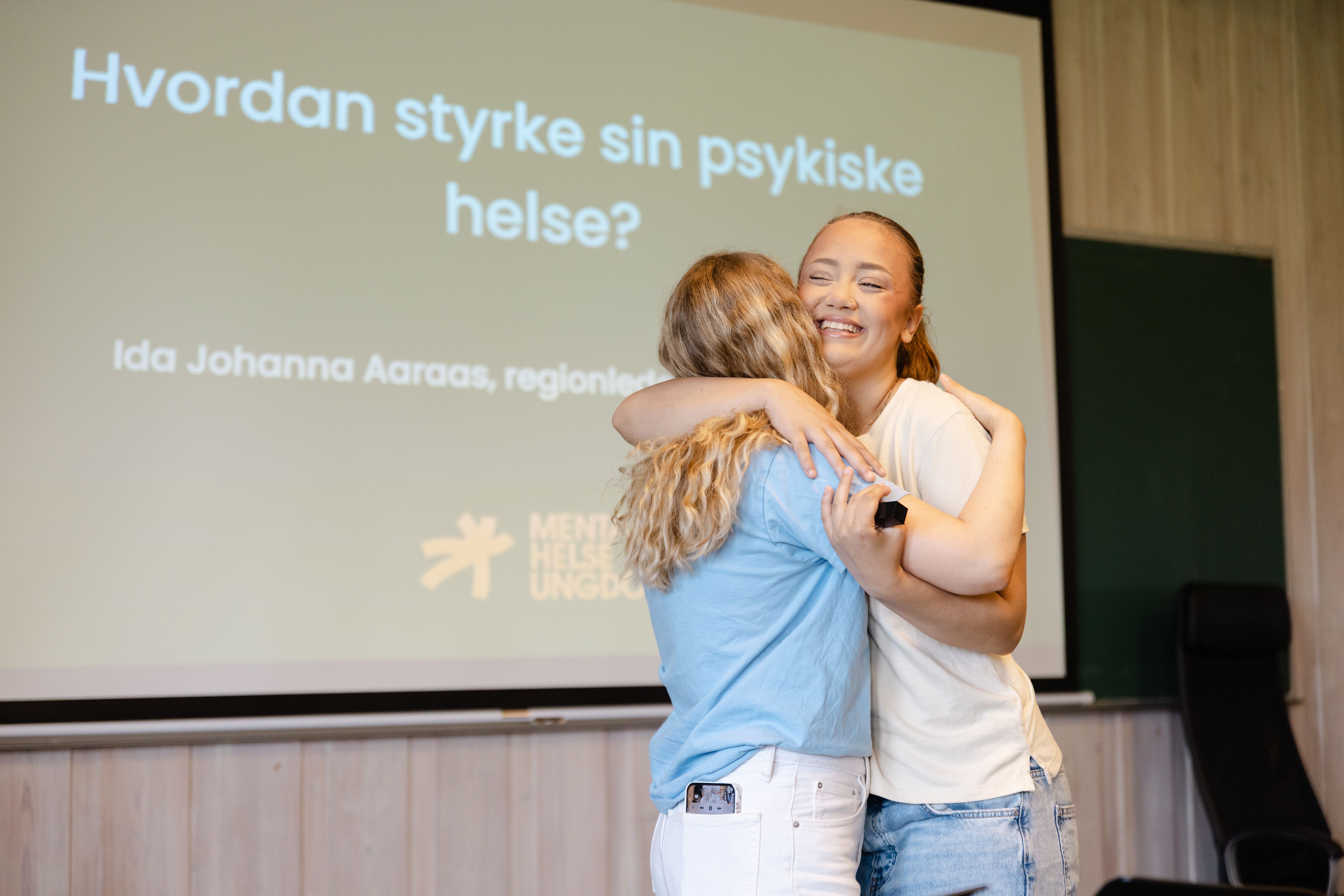 To personer som klemmer foran storskjerm