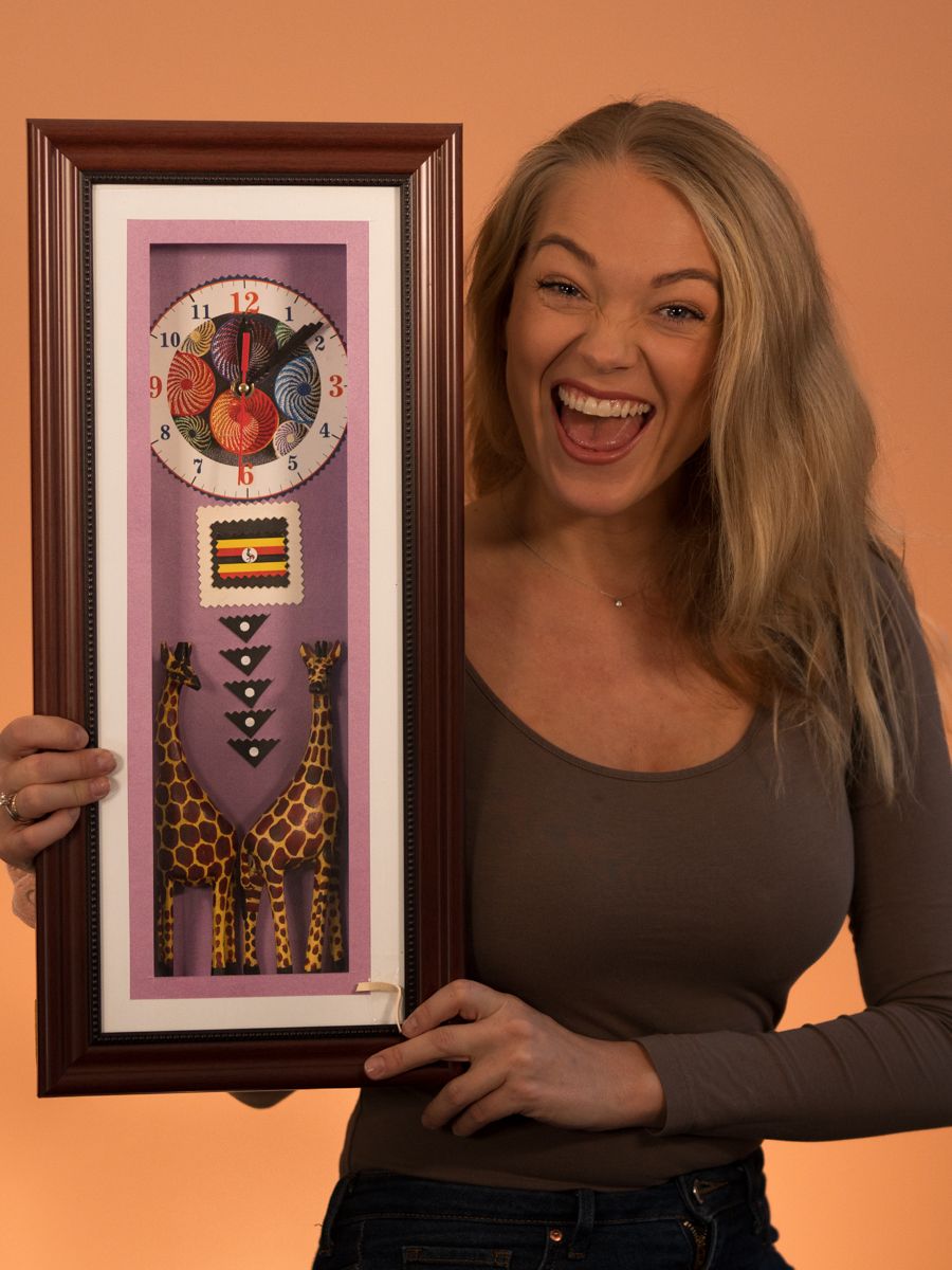 Uformelt bilde av Tuva hvor hun smiler mens hun holder opp en klokke fra Uganda