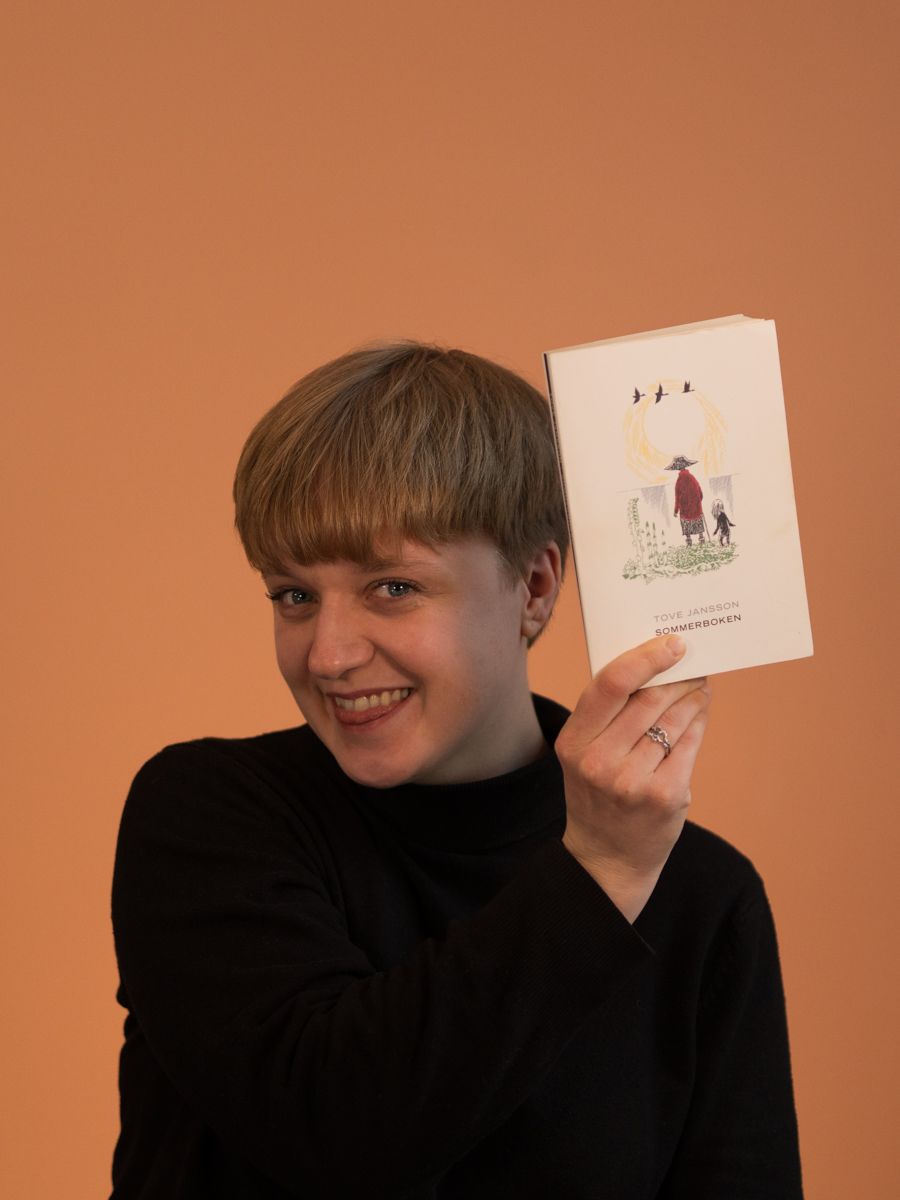 Uformelt bilde av Ingeborg som holder opp en bok