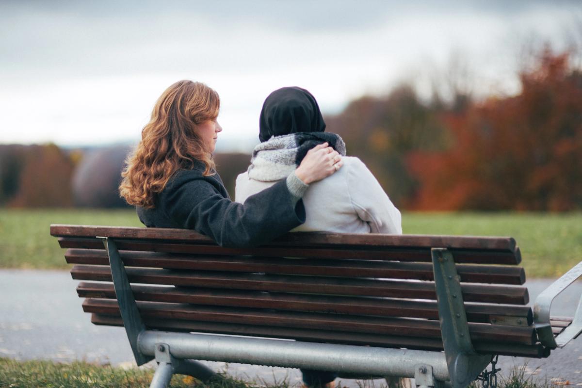 2 jenter på ben som holder rundt hverandre med ryggen til
