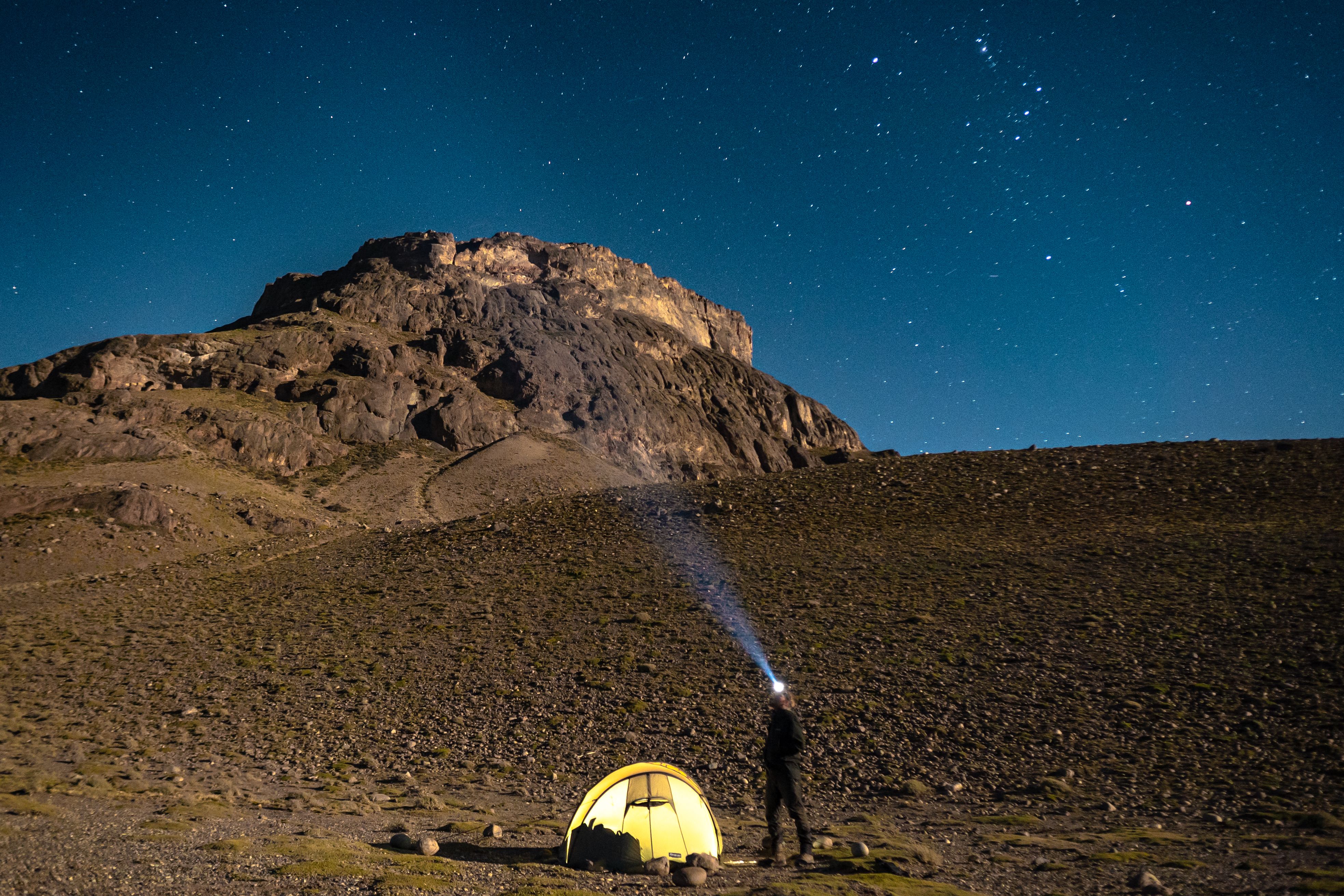 Landskapsbilde på kveldstid, med opplyst telt under stjernehimmel 