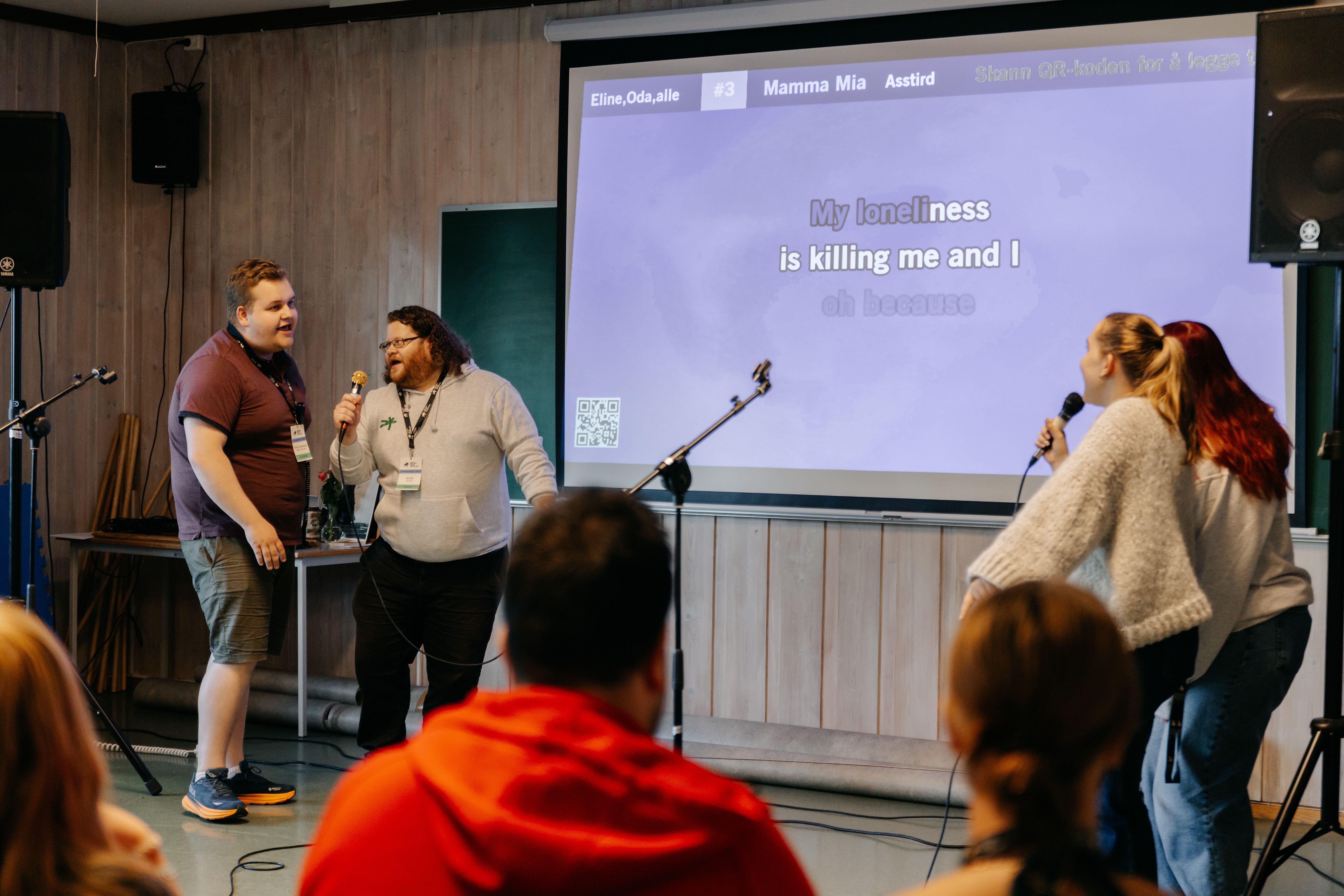 Karaokeskjerm og to som synger i en mikrofon